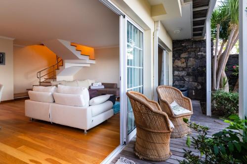 a living room with a white couch and wicker chairs at GuestReady - Madeiran paradise with ocean view in Funchal