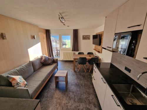 a living room with a couch and a kitchen with a table at Ferienhaus Mott in Lermoos