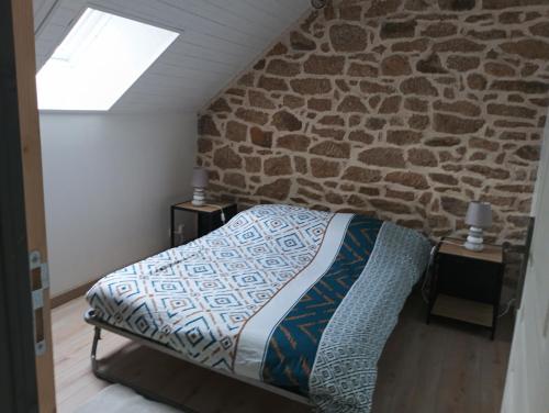 a bedroom with a bed and a stone wall at Maison de vacances in Languidic