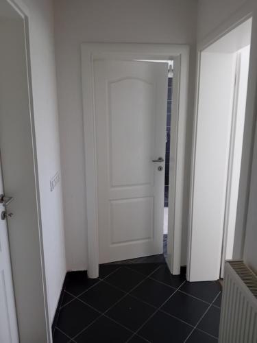 a hallway with a white door and a black tile floor at MEDINA in Sarajevo