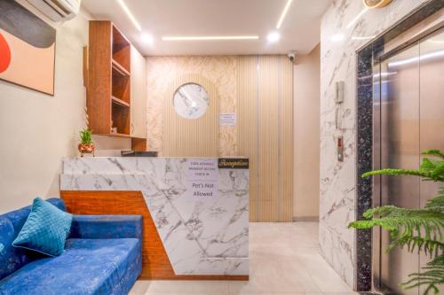 a lobby with a blue couch and a marble wall at Hotel Clover Inn by Onyx Group in Indore