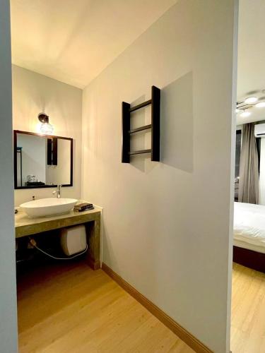 a bathroom with a sink and a mirror and a bed at C U Inn Bangkok in Bangkok