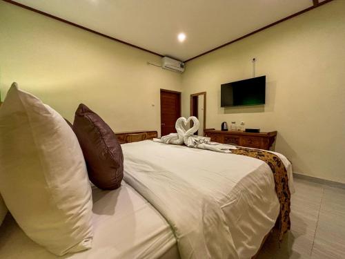 a large white bed in a room with a television at Buana Sari Villas by AGATA in Bangli