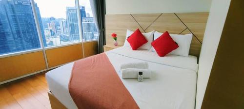 a bedroom with a bed with red pillows and a window at Sky Suites KLCC by TD Luxe Global in Kuala Lumpur