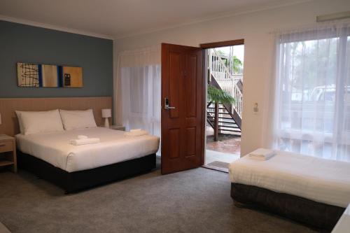 a bedroom with two beds and a door to a balcony at Kaloha Holiday Resort Phillip Island in Cowes