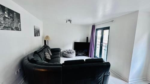 a black leather couch in a living room with a window at Ground Floor Beach Front Apartment in Swansea