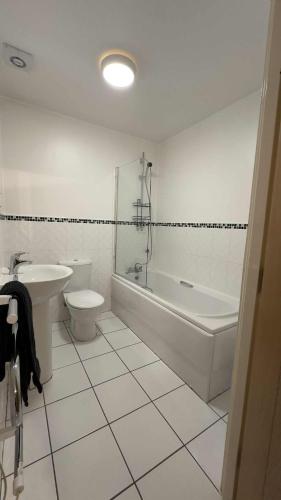 a bathroom with a tub and a toilet and a sink at Ground Floor Beach Front Apartment in Swansea