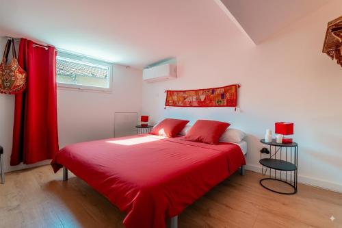 una camera da letto con un letto con lenzuola rosse e una finestra di TIKAZ Béziers - Appartement - 2 Chambres Hyper Centre a Béziers