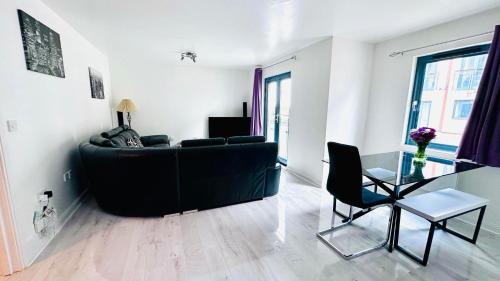 a living room with a black couch and a glass table at Ground Floor Beach Front Apartment in Swansea