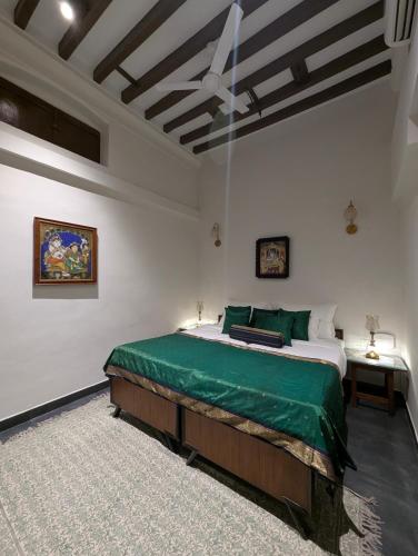a bedroom with a large bed with a green blanket at Nilayam by Luxunlock Private Villas in Jāmb