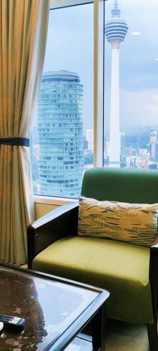 a room with a chair and a table and a window at Sky Suites KLCC by TD Luxe Global in Kuala Lumpur