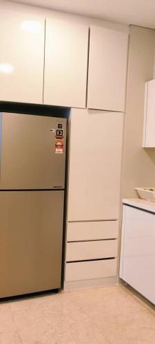 a kitchen with a refrigerator and white cabinets at Sky Suites KLCC by TD Luxe Global in Kuala Lumpur