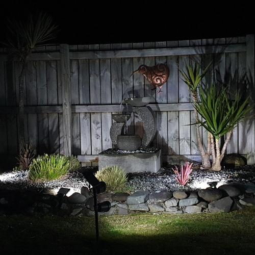 a garden with a fountain in front of a wooden fence at Moe Marie Sleep Peacefully in Turangi