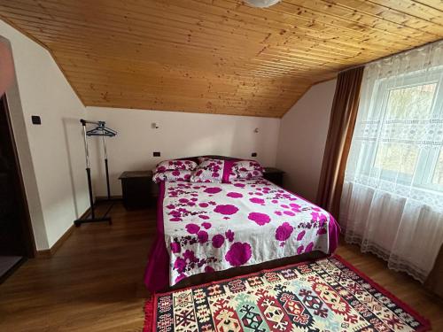 a bedroom with a bed with a floral bedspread at Casa Eliana in Călimăneşti
