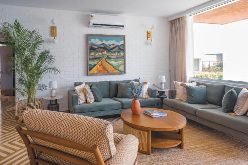 a living room with blue couches and a table at El Volar 2BHK Luxury Apartments 10 Minutes from Candolim Beach with Big common Pool, Fully Equipped Kitchen, 24x7 Security, Wifi in Nerul