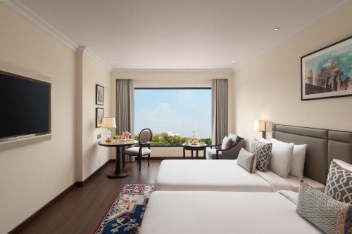 a hotel room with two beds and a television at Sarovar Portico Hanumangarh in Hanumāngarh