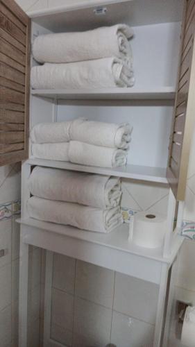 a stack of towels on a shelf in a bathroom at Vivenda para férias (Algarve) in Manta Rota