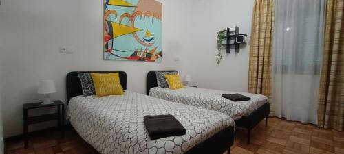 a bedroom with two beds and a painting on the wall at Casa da Rosa in Arcozelo