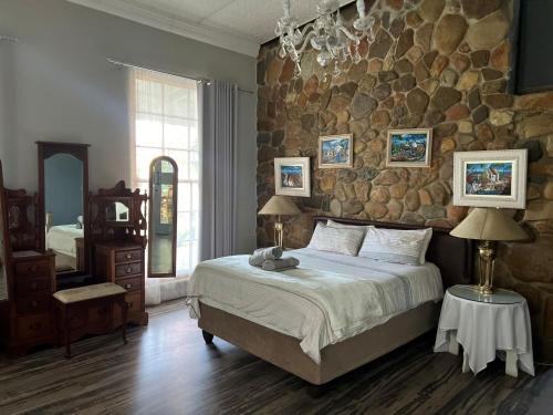 Un dormitorio con una cama grande y una pared de piedra. en Waterval Karoo Guest Farm, en Laingsburg