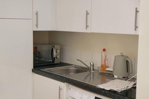 a kitchen with a sink and a microwave at Apartment - Sleeps 2 - Parking - Wi-Fi in Reading