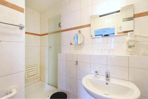 a white bathroom with a sink and a shower at Appartementhaus Strandnähe in Warnemünde