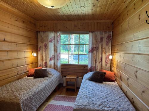 una camera da letto con due letti e una finestra di Levi Isorakka Holiday Cabin Pistotie a Kittilä