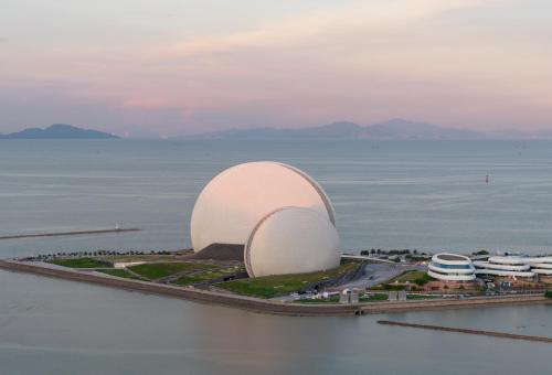 a large white building in the middle of the water at Holiday Inn Express Zhuhai Grand Theater by IHG in Zhuhai