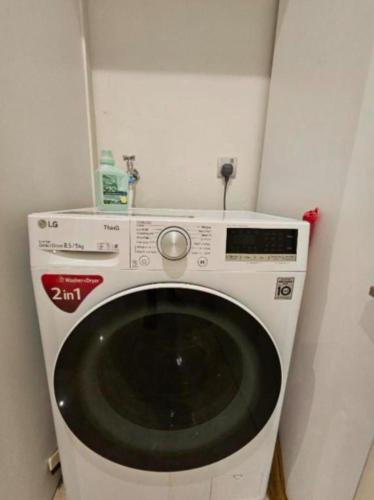 a white washing machine in a corner of a room at Sky Suites KLCC by TD Luxe Global in Kuala Lumpur