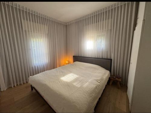 1 Schlafzimmer mit einem weißen Bett und 2 Fenstern in der Unterkunft Cottage near the beach in Kesar Shenaryahu