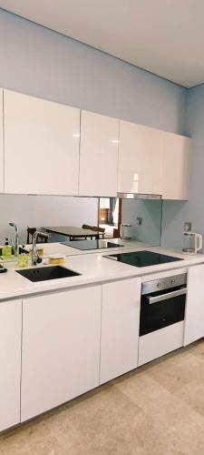 a white kitchen with white cabinets and a sink at Sky Suites KLCC by TD Luxe Global in Kuala Lumpur