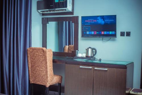 una stanza con una scrivania con una televisione e una sedia di Xanders Villa a Mama