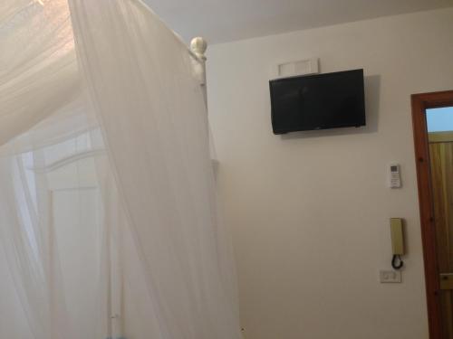 a room with a white curtain and a television on a wall at Appartamento Onda Marina in Polignano a Mare