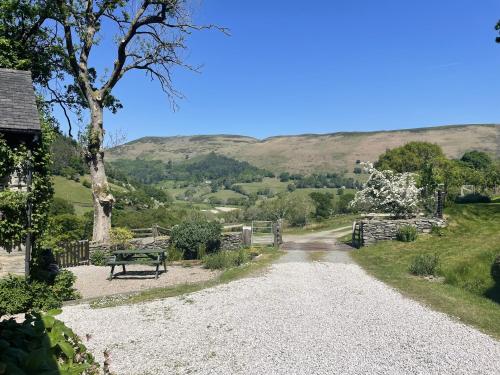 a gravel road with a bench and mountains in the background at Graig Las The Barn in Oswestry