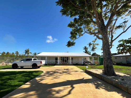 a white car parked in front of a house at Toafa Elidad Airport Lodge 