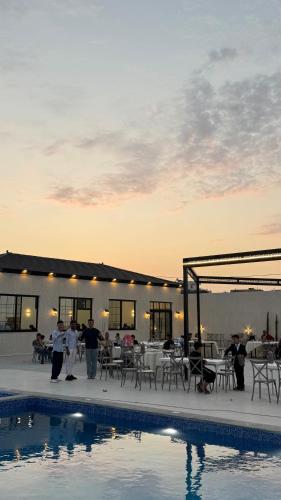 a group of people standing next to a swimming pool at olive tree farm and chalet - مزرعه و شاليه شجره الزيتون 