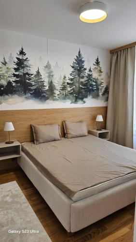 a bedroom with a large bed with a painting on the wall at Zlatni TRG in Zlatibor
