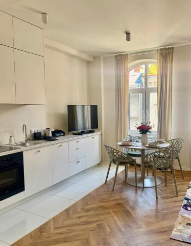 a kitchen with white cabinets and a table with chairs at Apartamenty Śródmiejska in Świebodzin