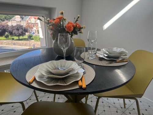a dining table with two plates and a vase with flowers at Apartamenty Śródmiejska in Świebodzin