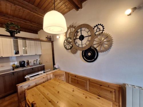 a kitchen with a wooden table and a clock on the wall at Appartamento Bellavista in Pievepelago