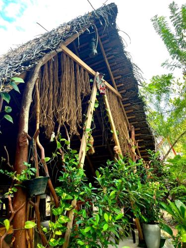 a house with a thatched roof with plants around it at Sigiri Birds Hostel in Sigiriya