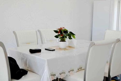 a white table with a vase of flowers on it at Toafa Elidad Airport Lodge 