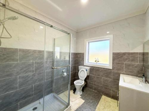 a bathroom with a shower and a toilet and a sink at Toafa Elidad Airport Lodge 