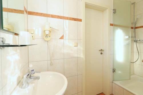 a white bathroom with a sink and a shower at Appartementhaus Strandnähe in Warnemünde