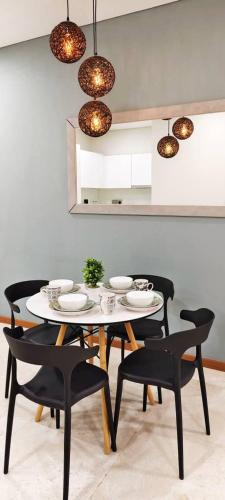 a dining room with a white table and black chairs at Sky Suites KLCC by TD Luxe Global in Kuala Lumpur