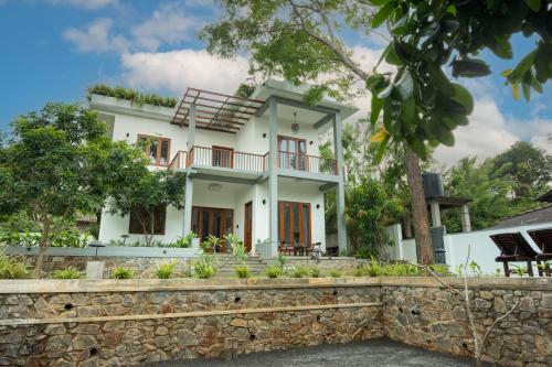 a white house with a stone wall at Villa Sathkara in Tangalle