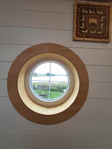 a round window in a wall with a picture at Mazurska Latarnia z prywatną plażą i stawem in Rydzówka