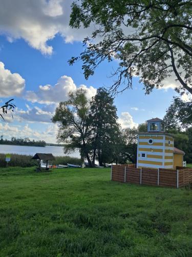 a building in a field next to a body of water at Mazurska Latarnia z prywatną plażą i stawem in Rydzówka