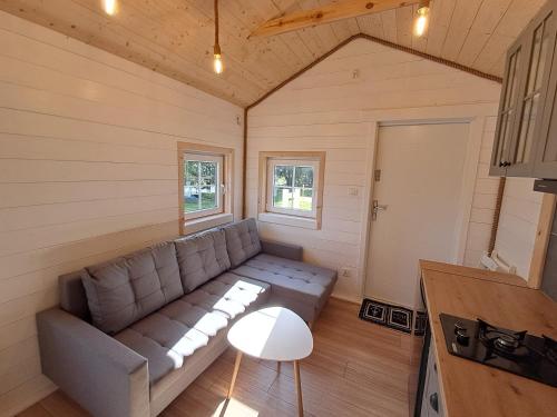 a living room with a couch in a tiny house at Mazurska Latarnia z prywatną plażą i stawem in Rydzówka