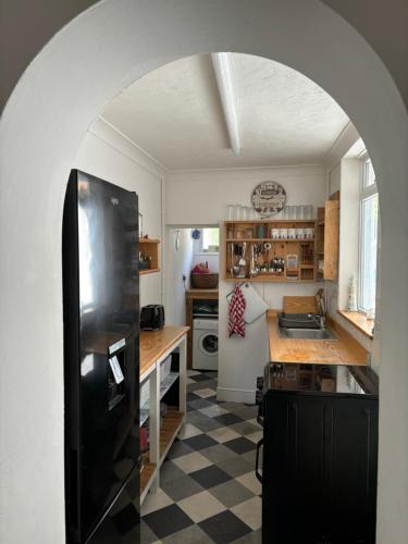a kitchen with a black refrigerator and a checkered floor at “The Reach” Lovely 2 bed house in Gorleston on Sea in Gorleston-on-Sea