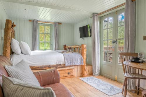 ein Schlafzimmer mit einem Bett, einer Couch und einem Fernseher in der Unterkunft Juniper Lodge, Coniston, Lake District in Coniston